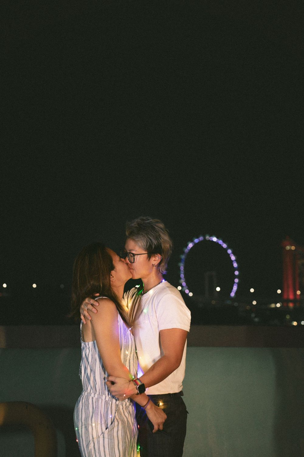 A romantic nighttime moment with a ferris wheel glowing in the background.
