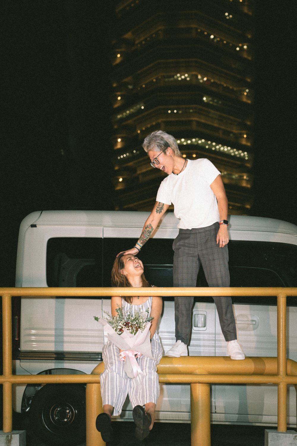 A nighttime scene with two people on different levels of a concrete barrier.