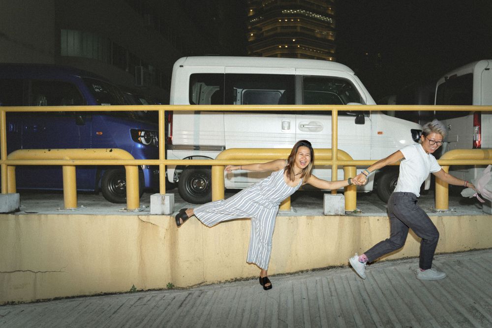 Playful pose on concrete barriers at night with a white van in the background.