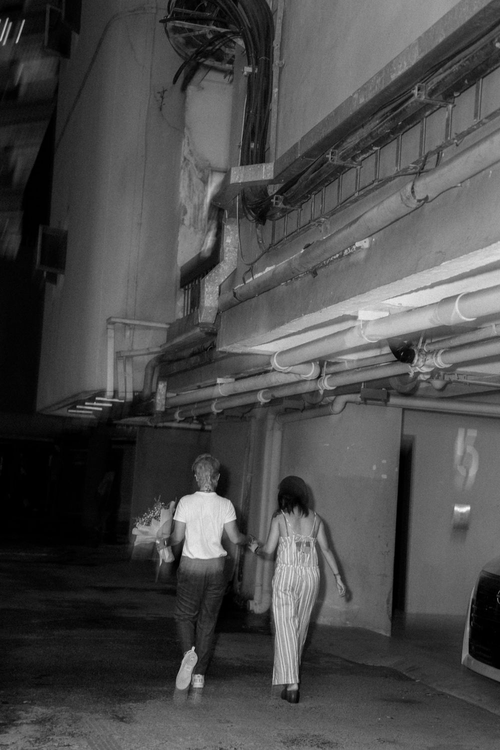 A black and white photo of two people walking through what appears to be a parking structure.