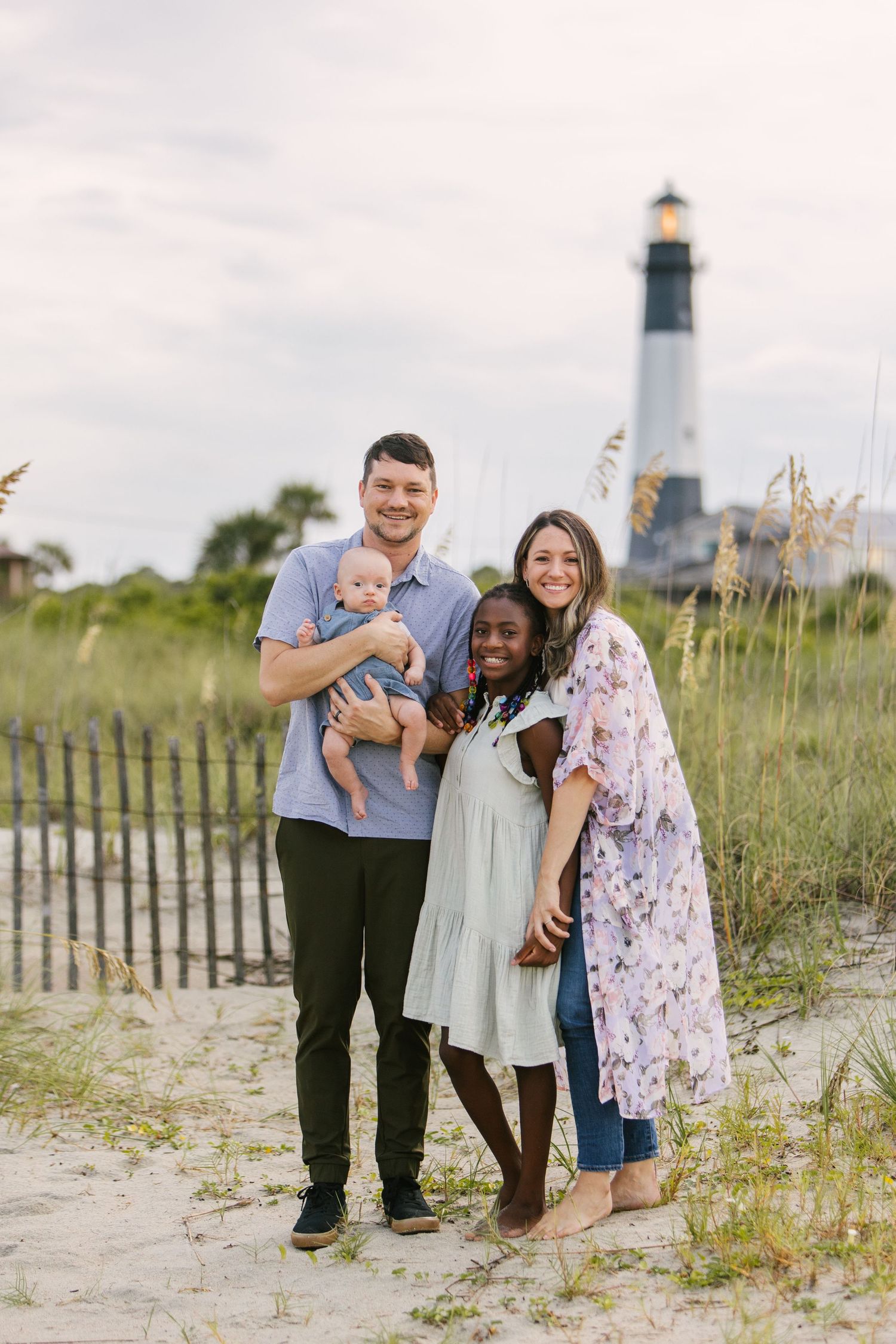 Family portrait at lighthouse with sea grass in foreground.