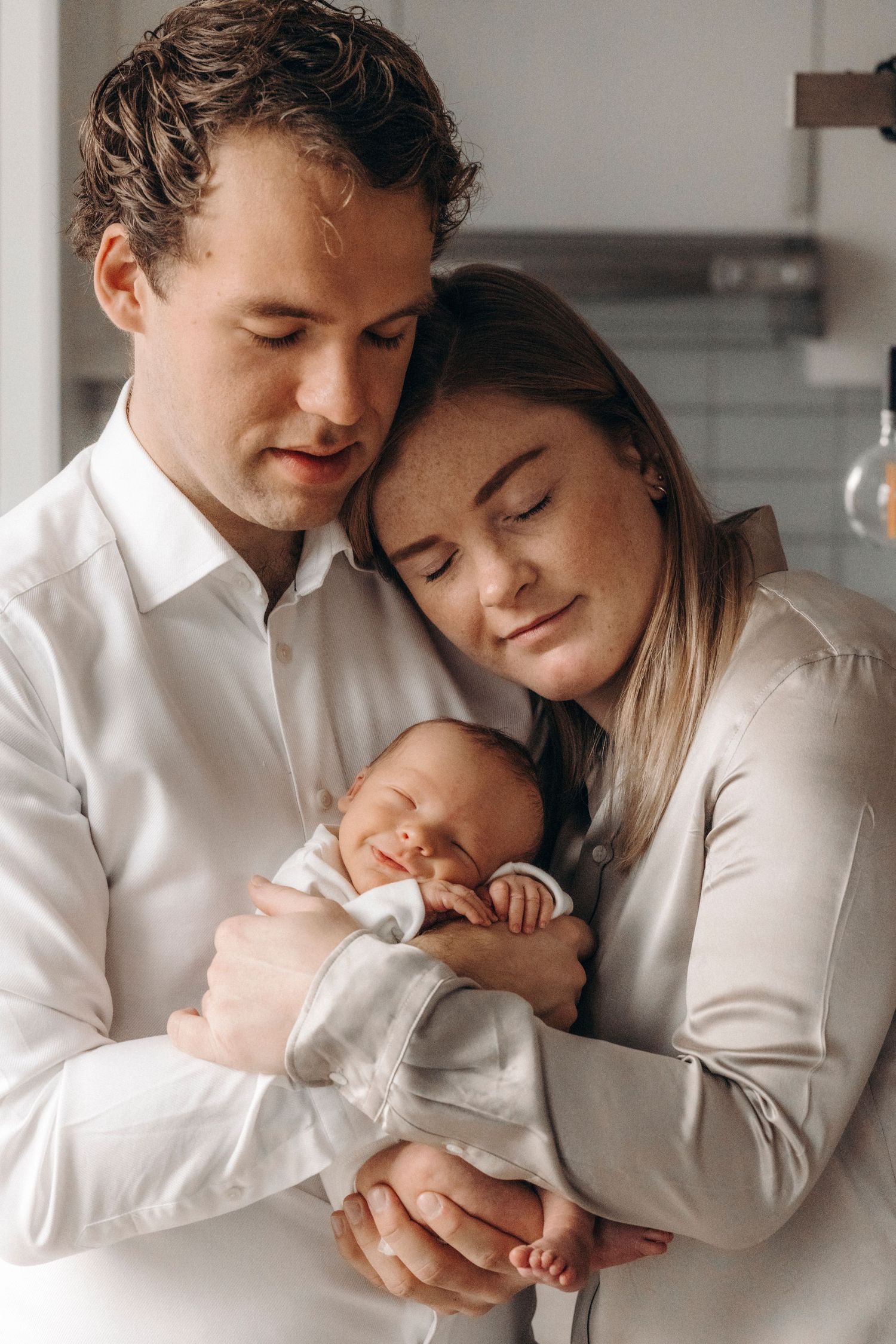 Intimate family moment as parents cuddle their sleeping newborn.