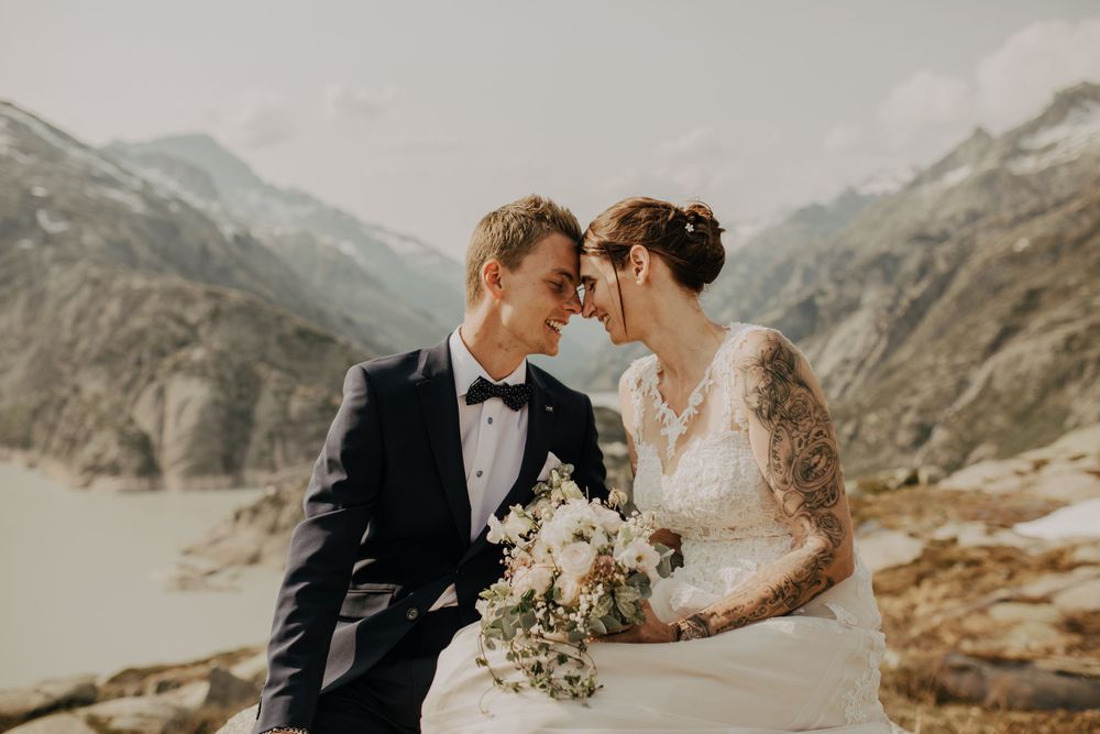 Newlyweds sharing an intimate moment against a dramatic mountain landscape backdrop.
