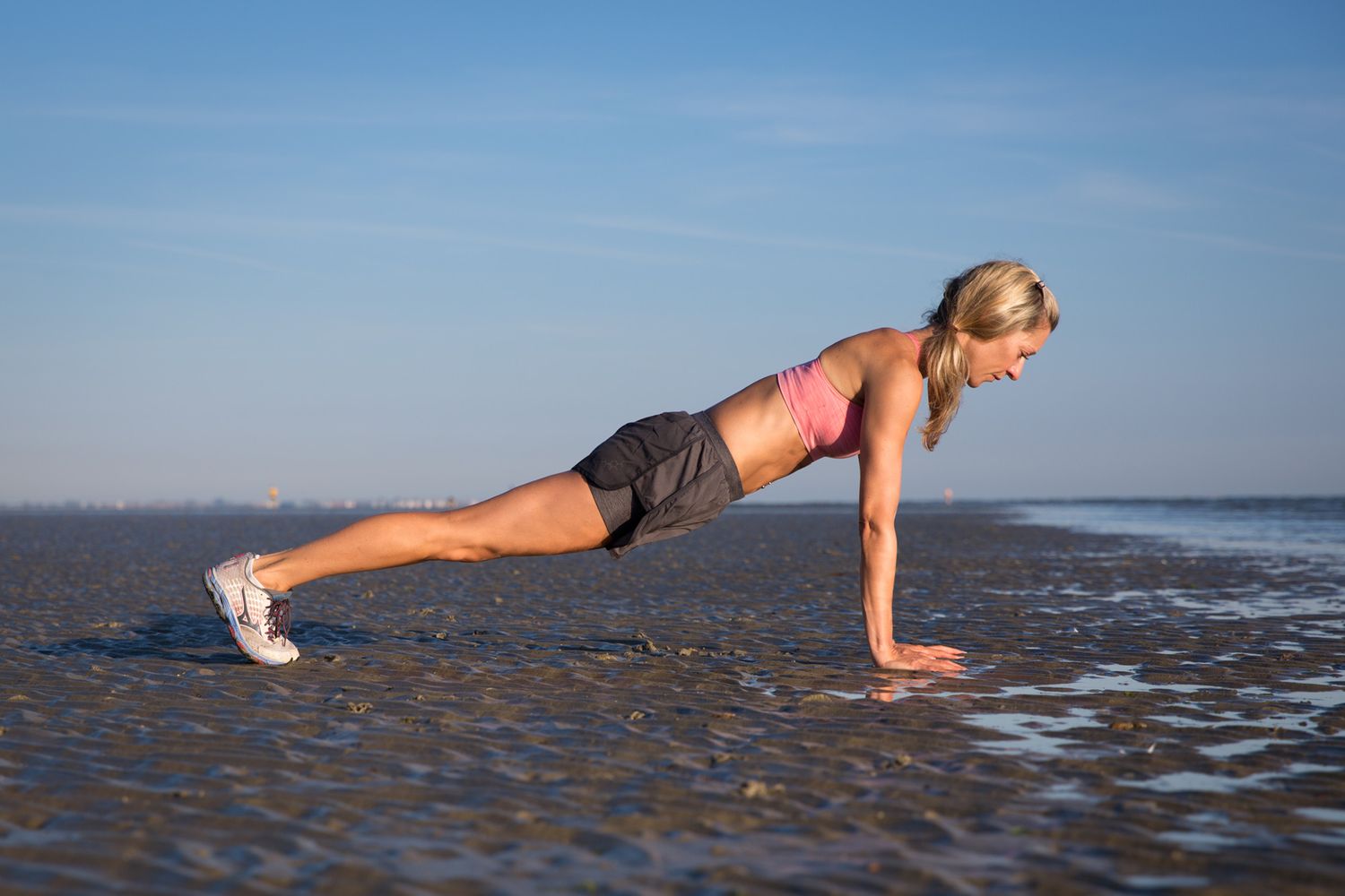 Person doing plank exercise on beach at sunrise during business branding photoshoot.