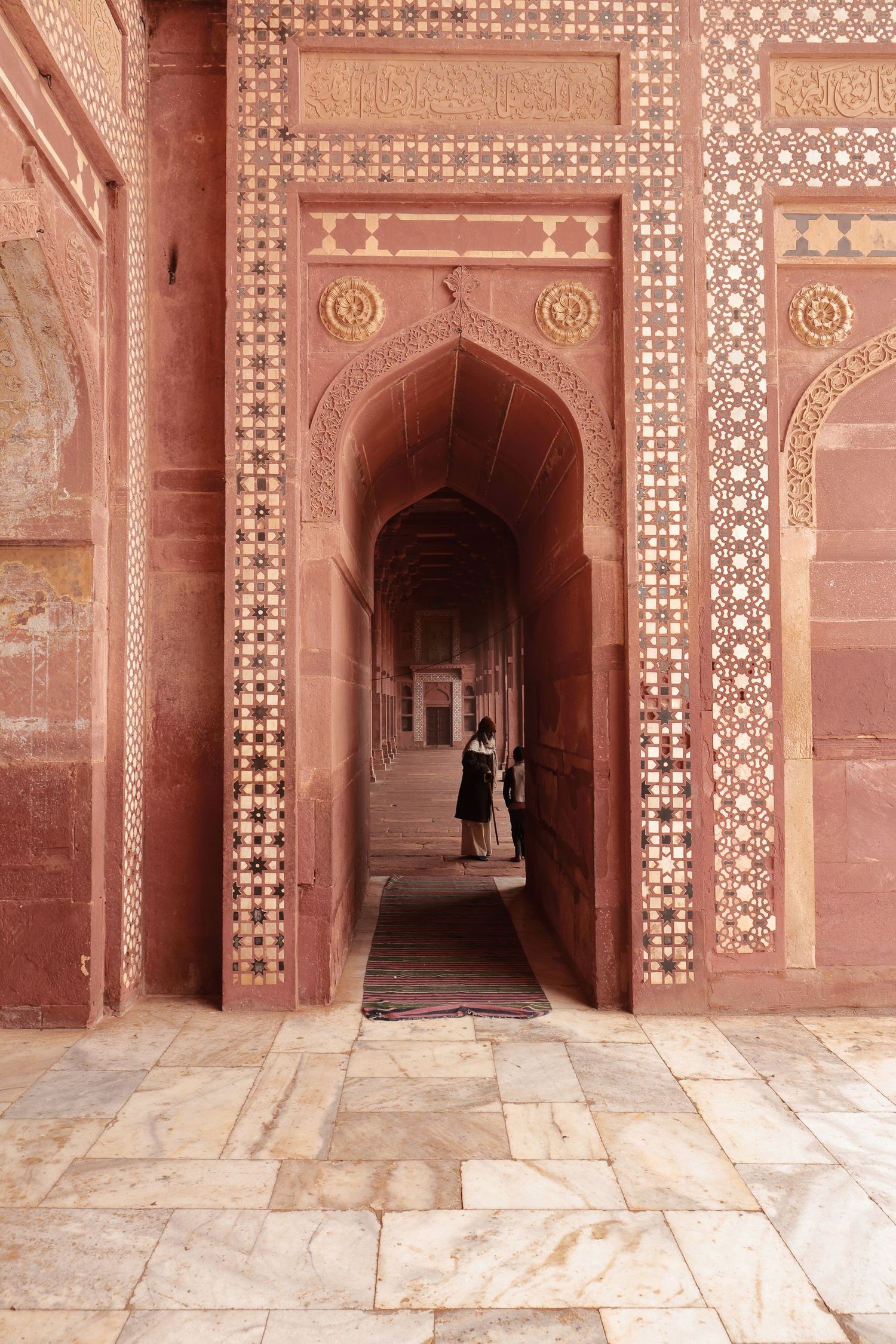 Ornate red sandstone archway with geometric patterns and inlaid details in a historic Indian palace.