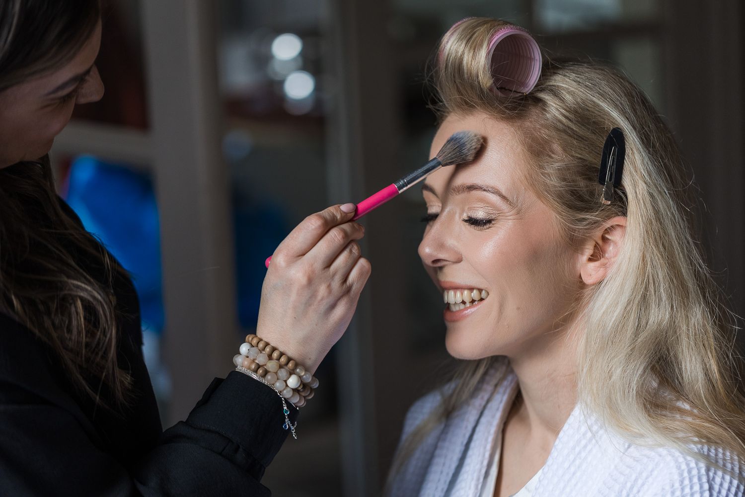 Professional makeup artist applying cosmetics during bridal preparation.