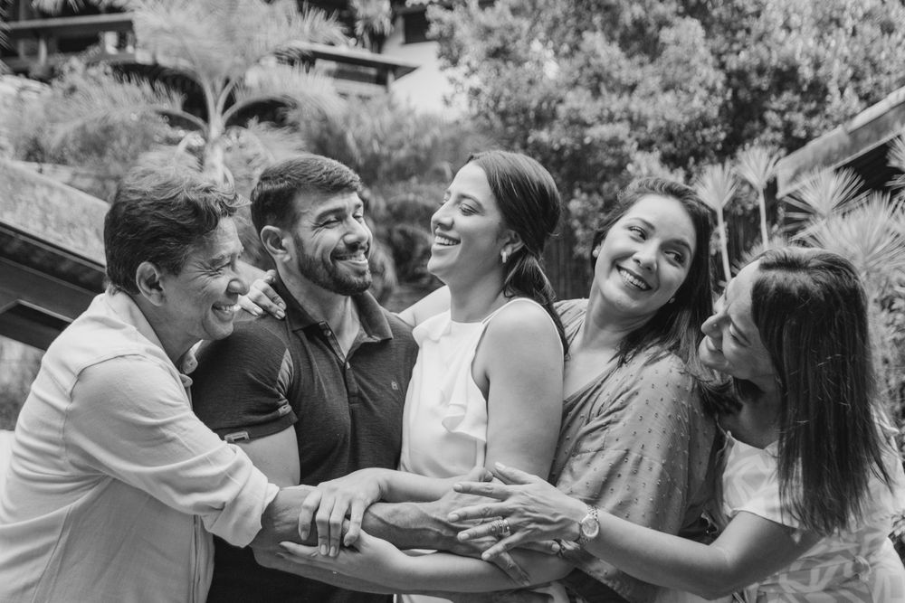 Group sharing joyful laughter while gathered together outdoors in black and white photo.