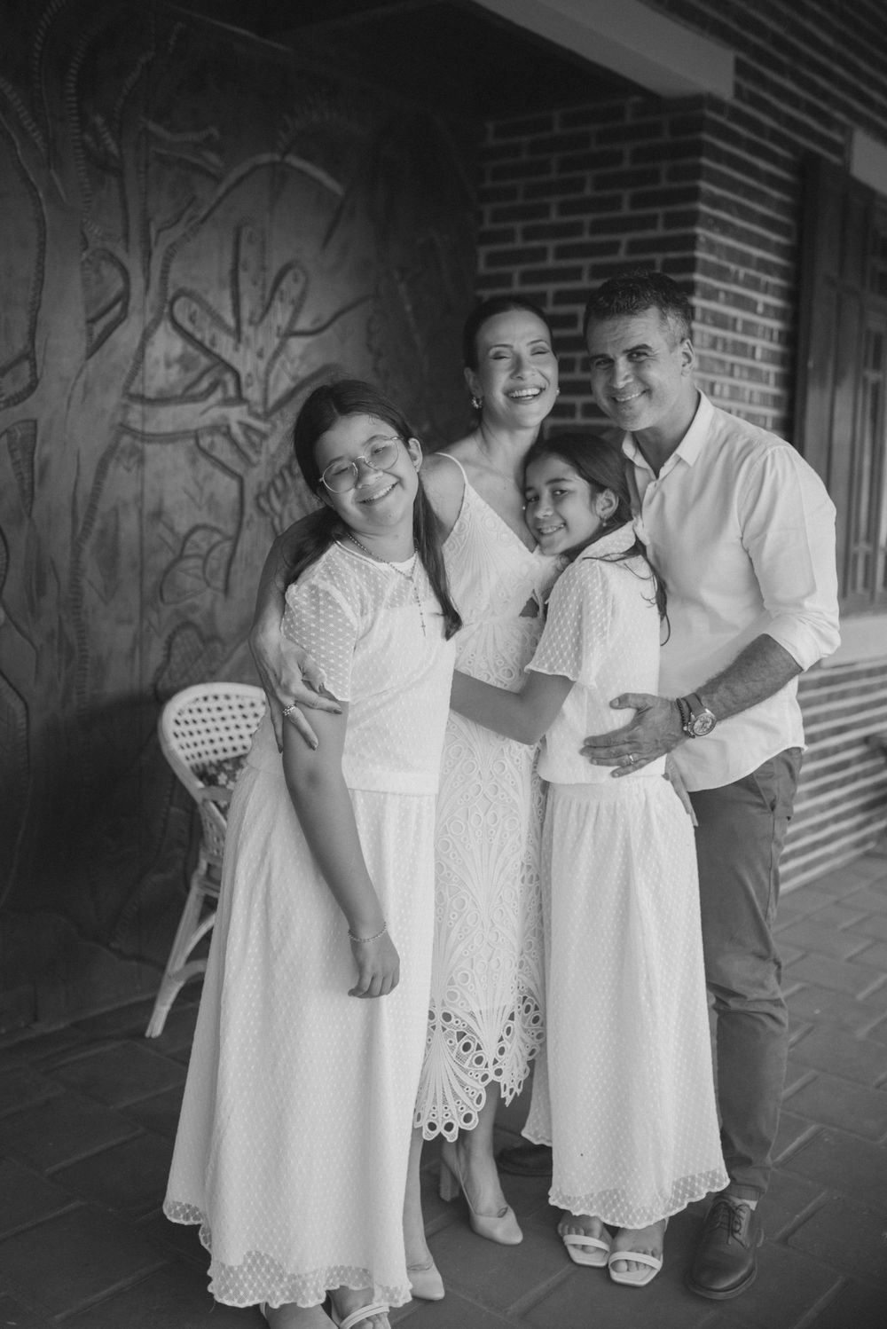 A black and white portrait of a family group in coordinating white outfits.