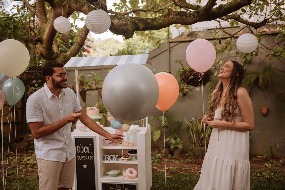 Outdoor gender reveal party scene with balloons and decorative setup in garden setting.