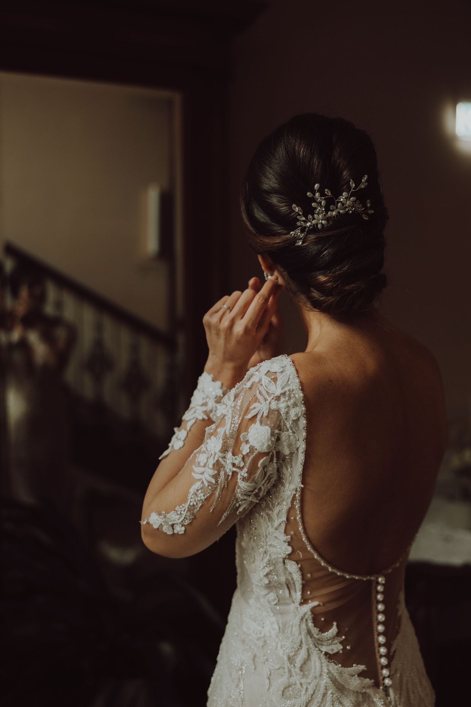 Back view of bride in lace dress with delicate hair accessory.