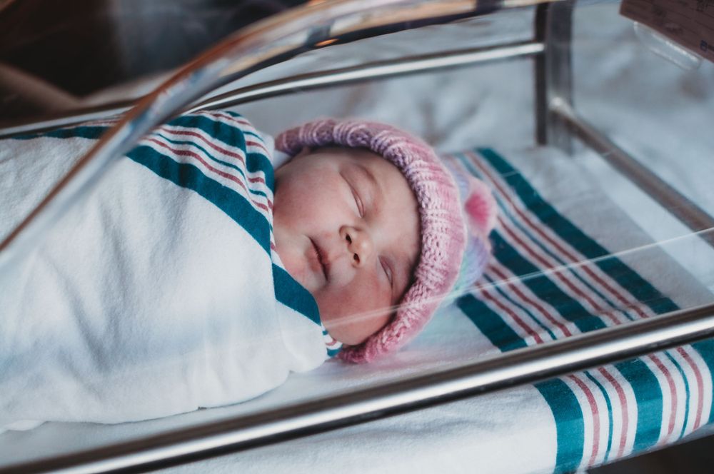 Fresh 48 hospital newborn photography - parents meeting baby for the first time in Dickinson, ND - newborn swaddled in hospital bassinet