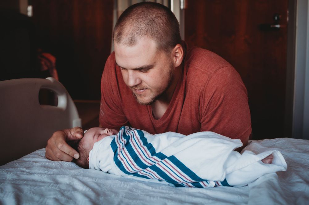 Dad comforting newborn baby in the first hours of life - lifestyle photographer serving Dickinson and southwest North Dakota