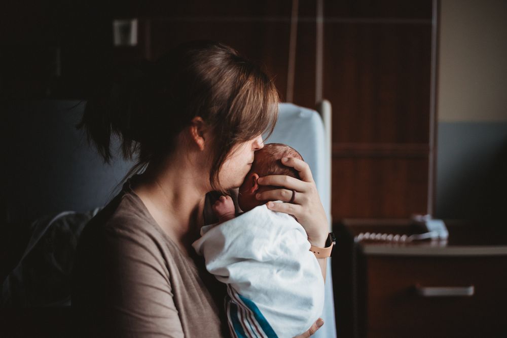 Mom comforts newborn baby - natural light photographer serving labor and delivery at CHI St. Alexius Health Dickinson, ND
