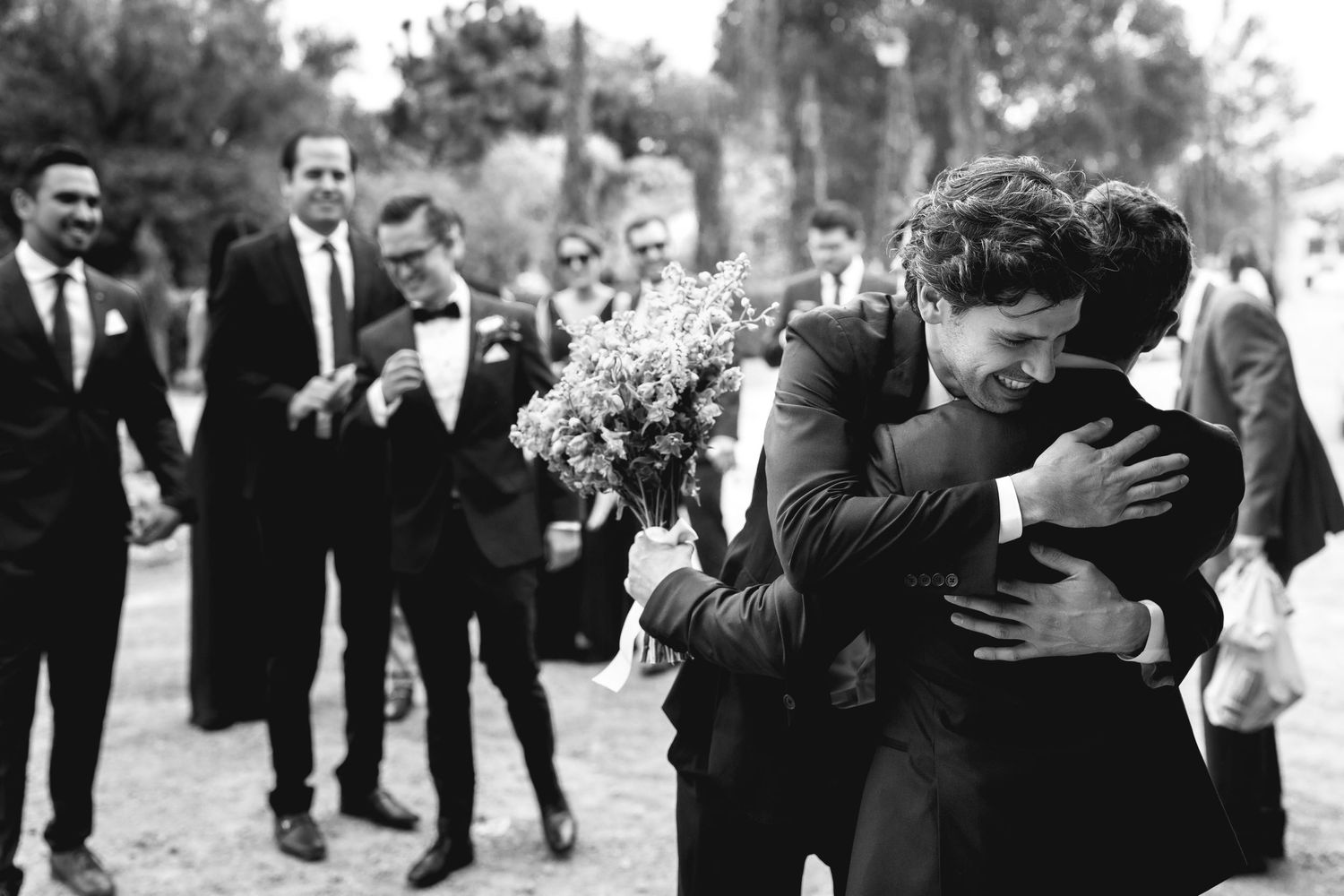 Emotional black and white wedding moment captured between guests during outdoor celebration.