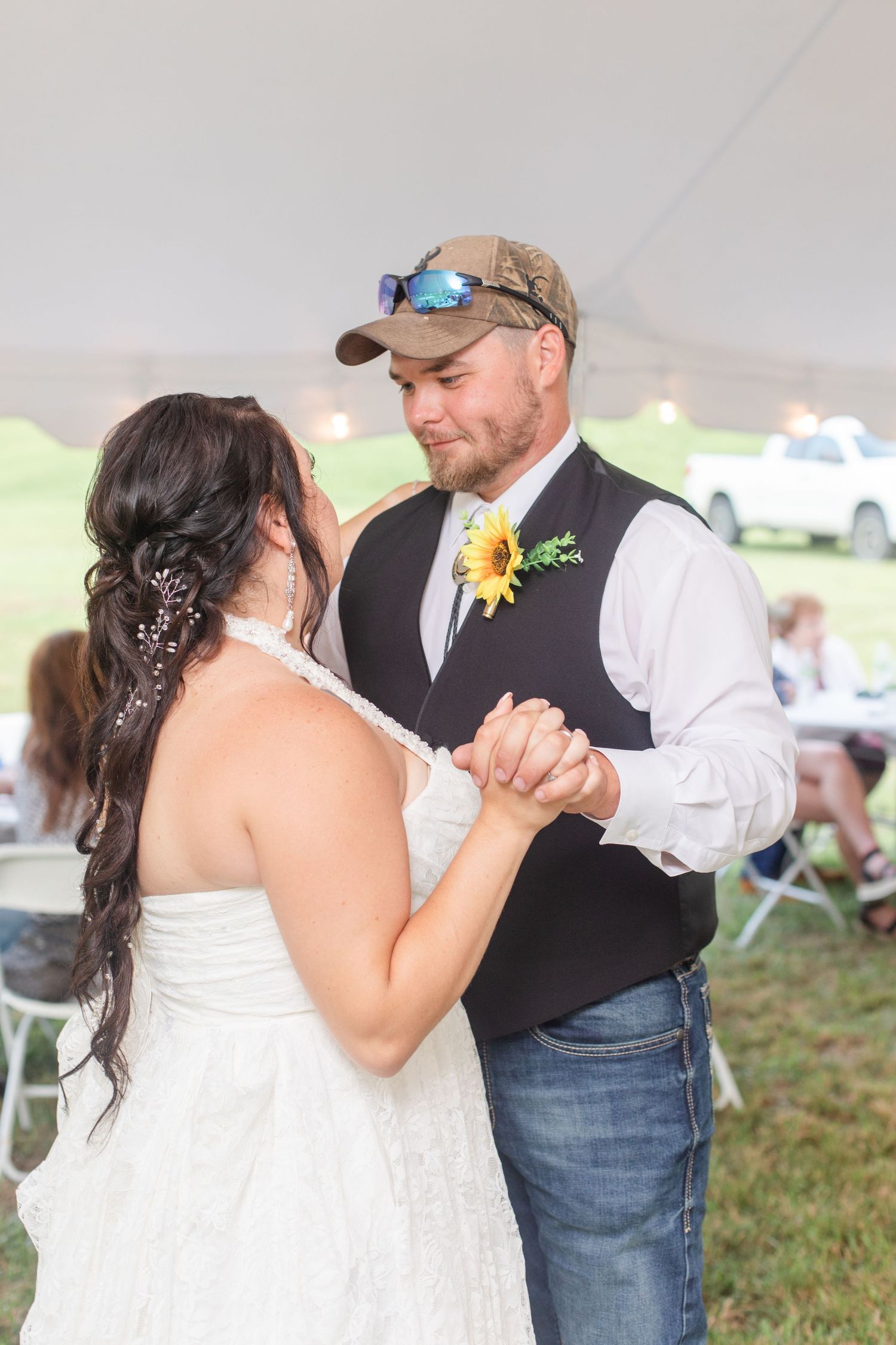 Couple sharing their first dance under a white tent at an outdoor wedding reception.