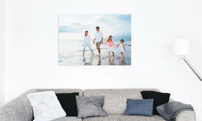 Beach-themed canvas print displayed above grey and black throw pillows on modern sofa.
