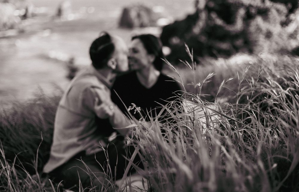 a black and white focused on the grass in front of an image of a man and woman enjoying each others company