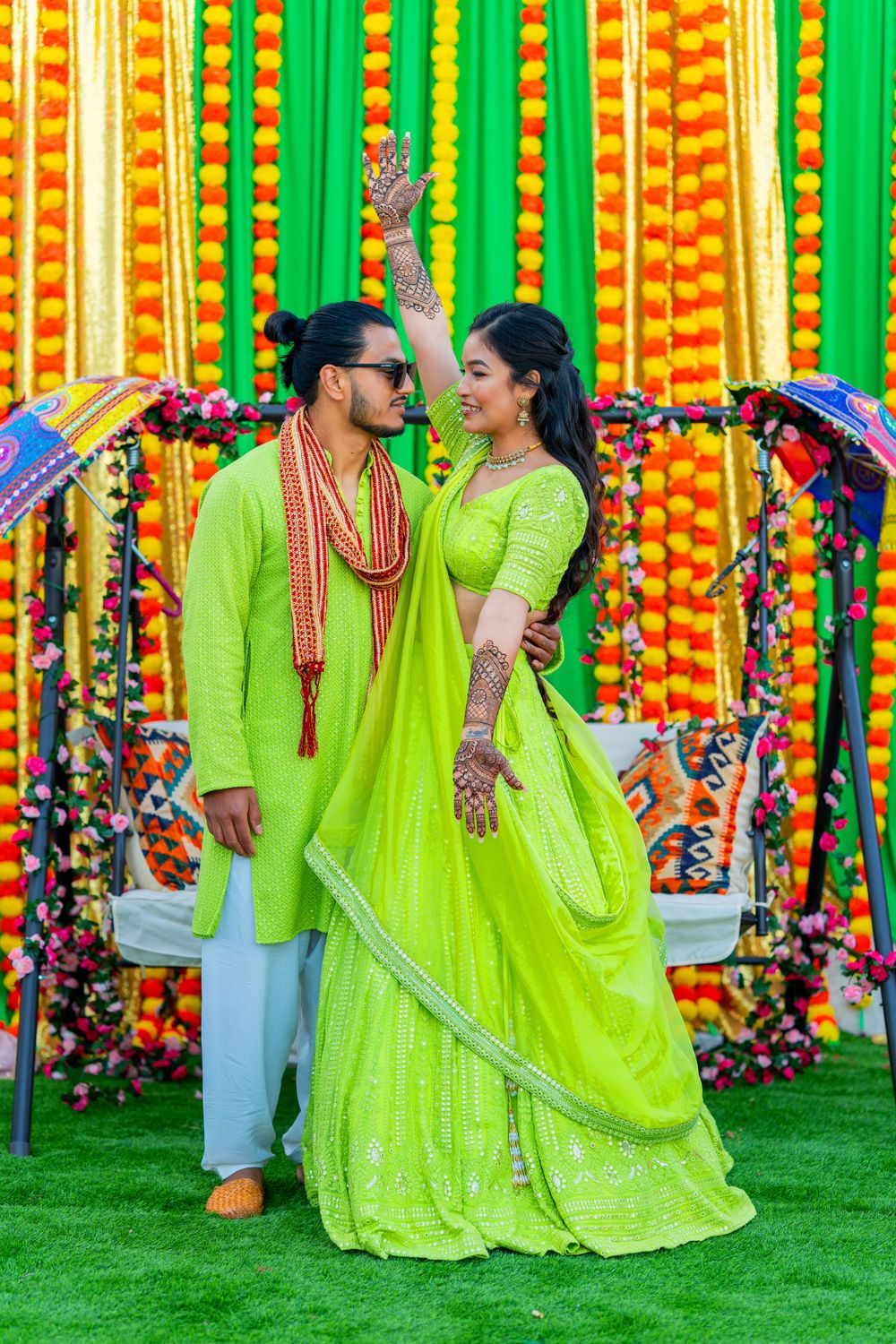 Couple in coordinated lime green outfits sharing a moment under decorative umbrellas.