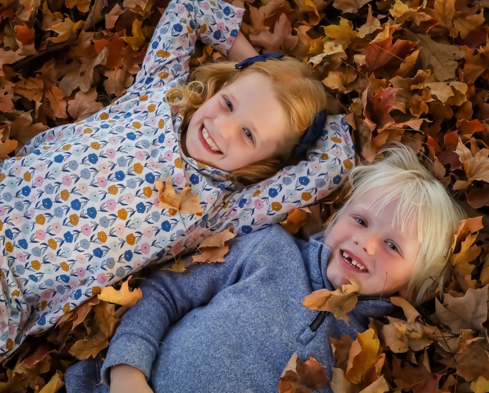 Couple lying in autumn leaves during a seasonal outdoor photoshoot.