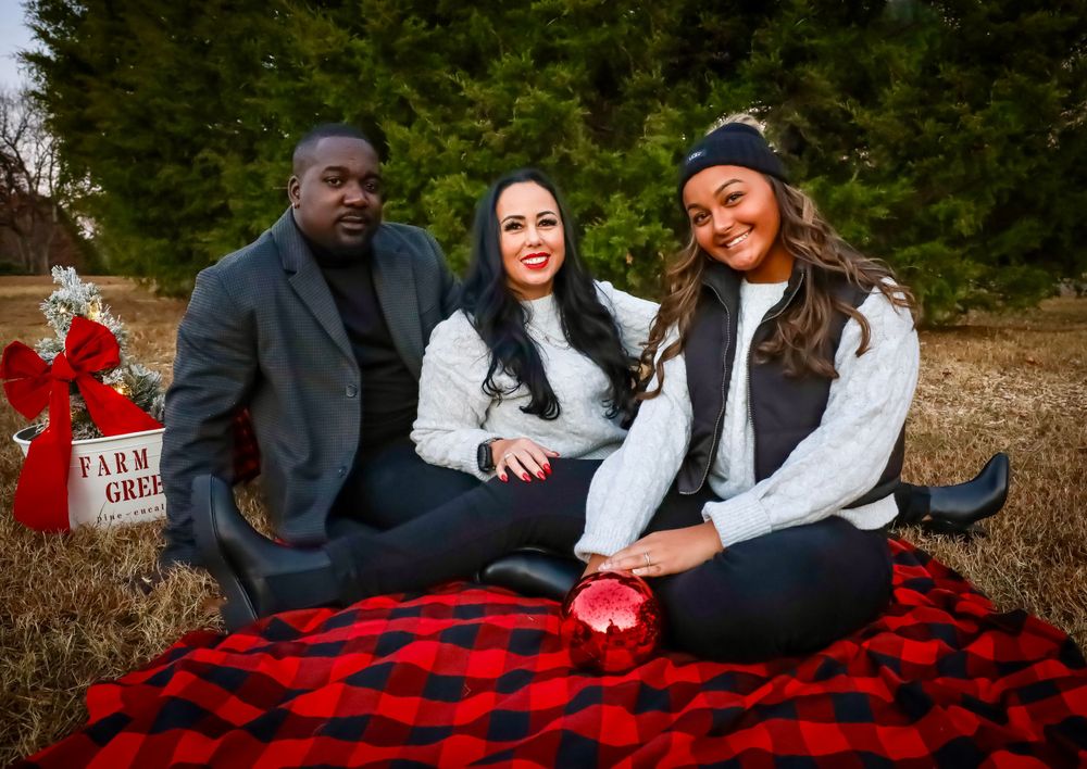 Family lounging on a red buffalo plaid blanket during an autumn photoshoot.