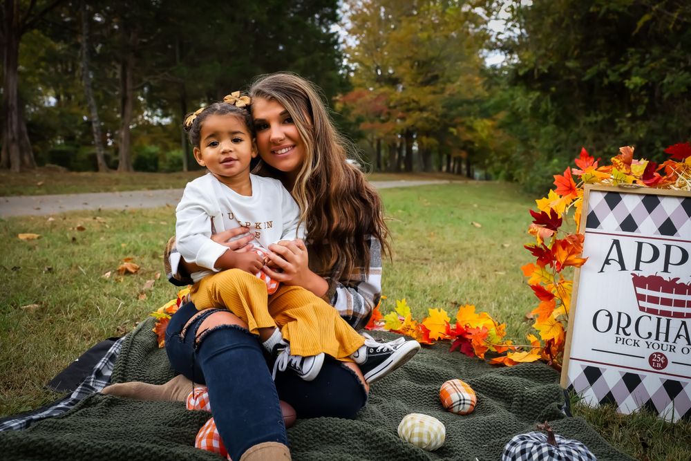 Fall themed photoshoot setup with pumpkins and decorative signs outdoors.
