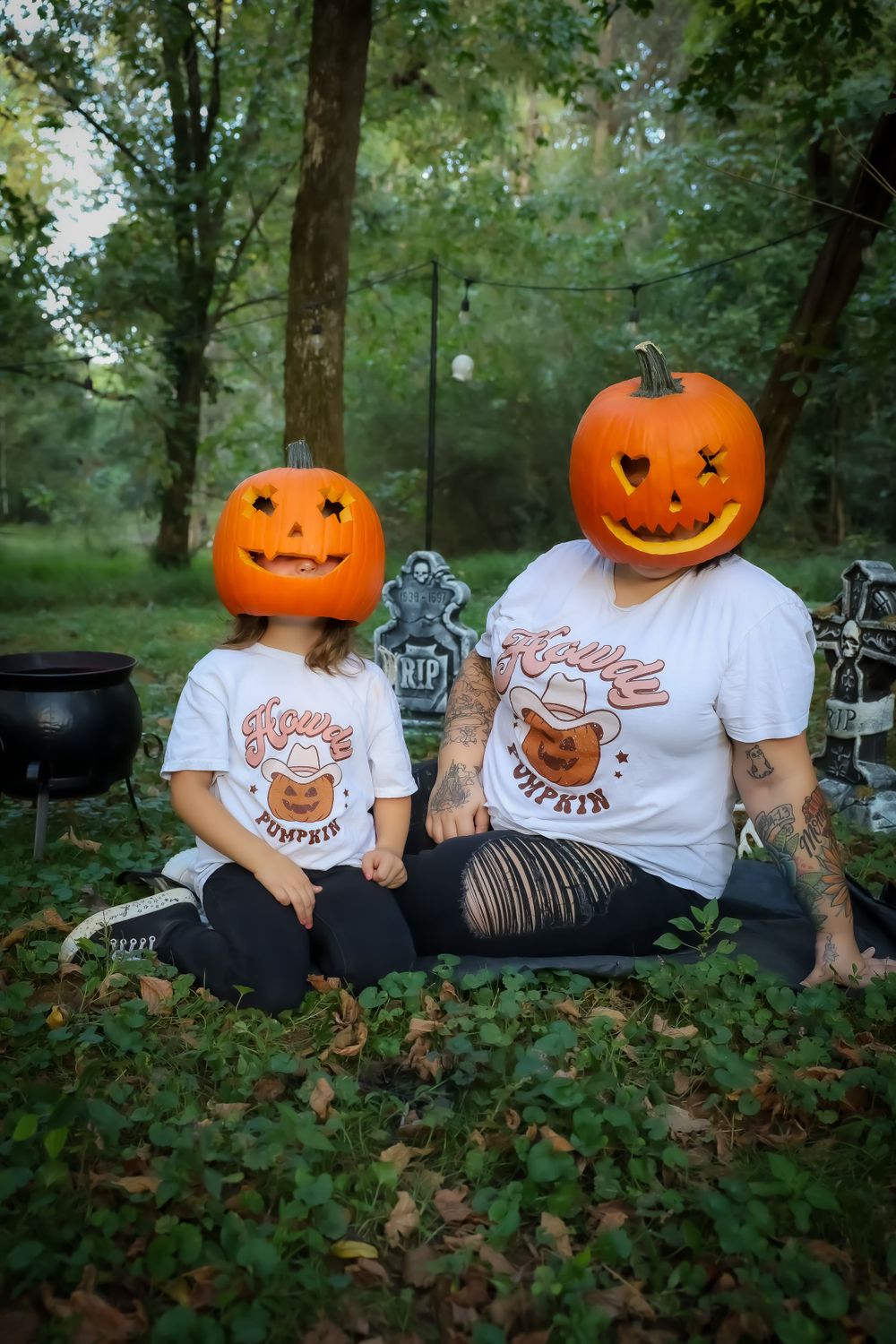 Creative Halloween themed photo with jack-o-lantern heads and matching t-shirts in outdoor setting.