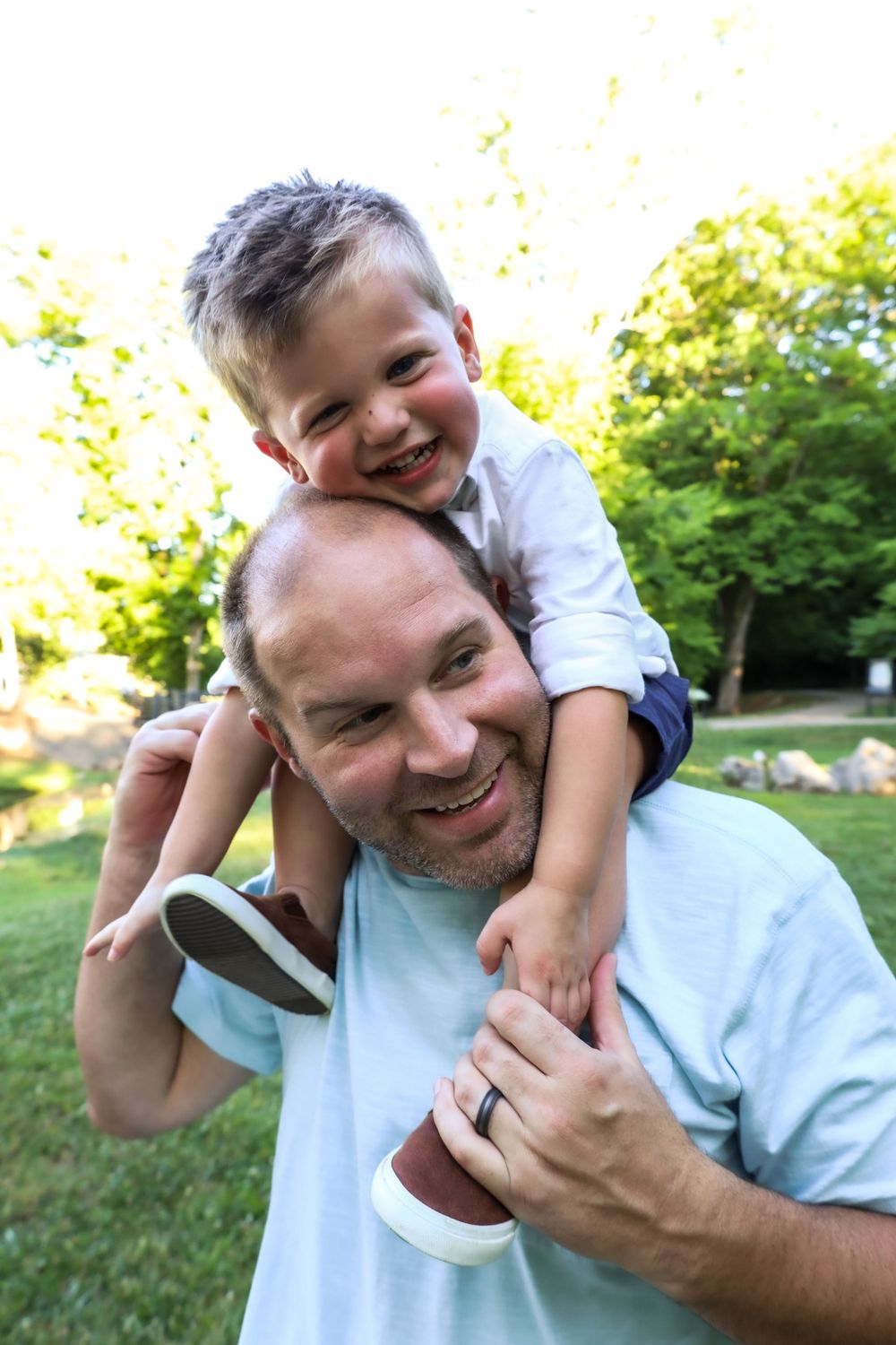 A playful moment between parent and child outdoors on a sunny day.