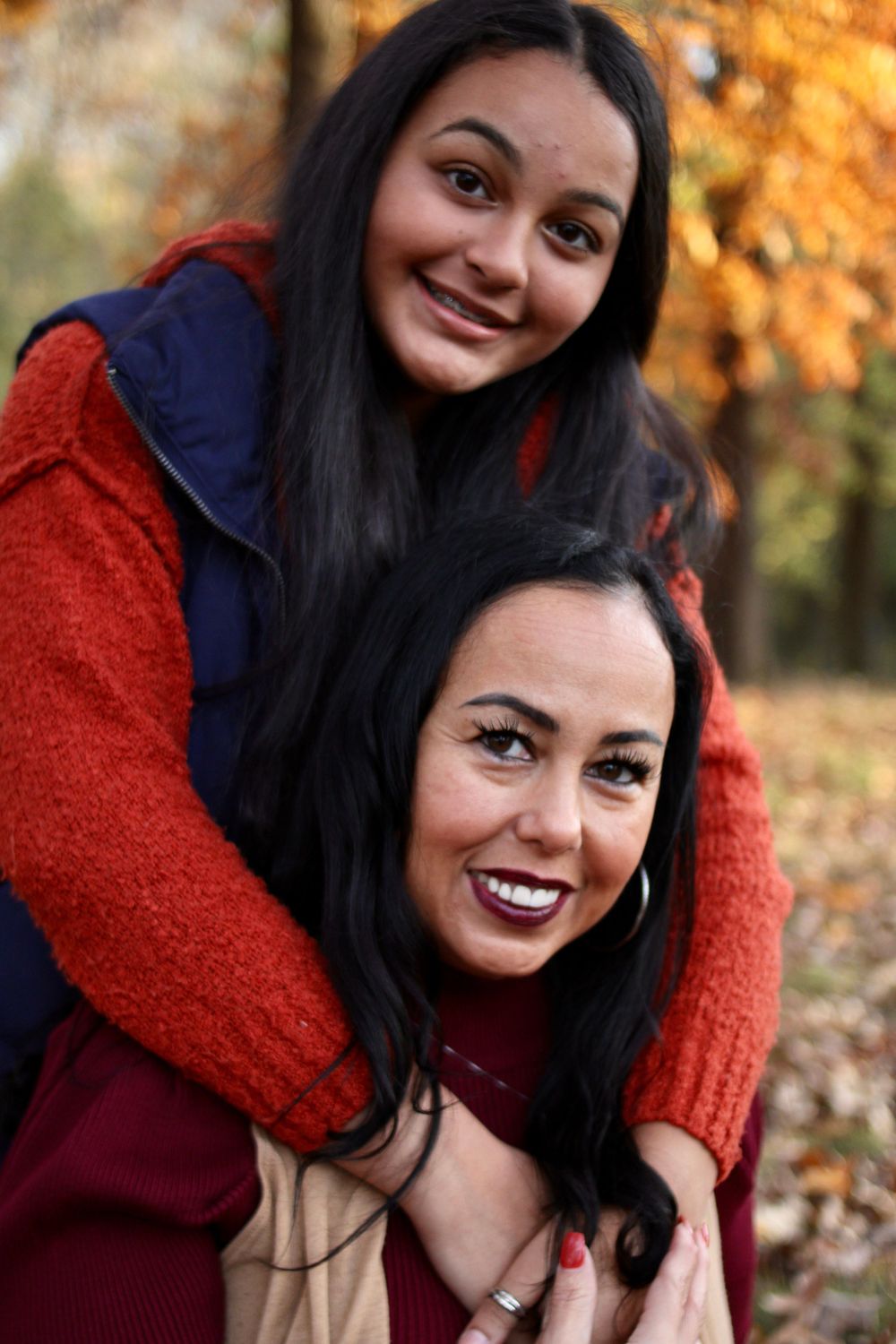 Fall family photoshoot with vibrant autumn colors and foliage in background.