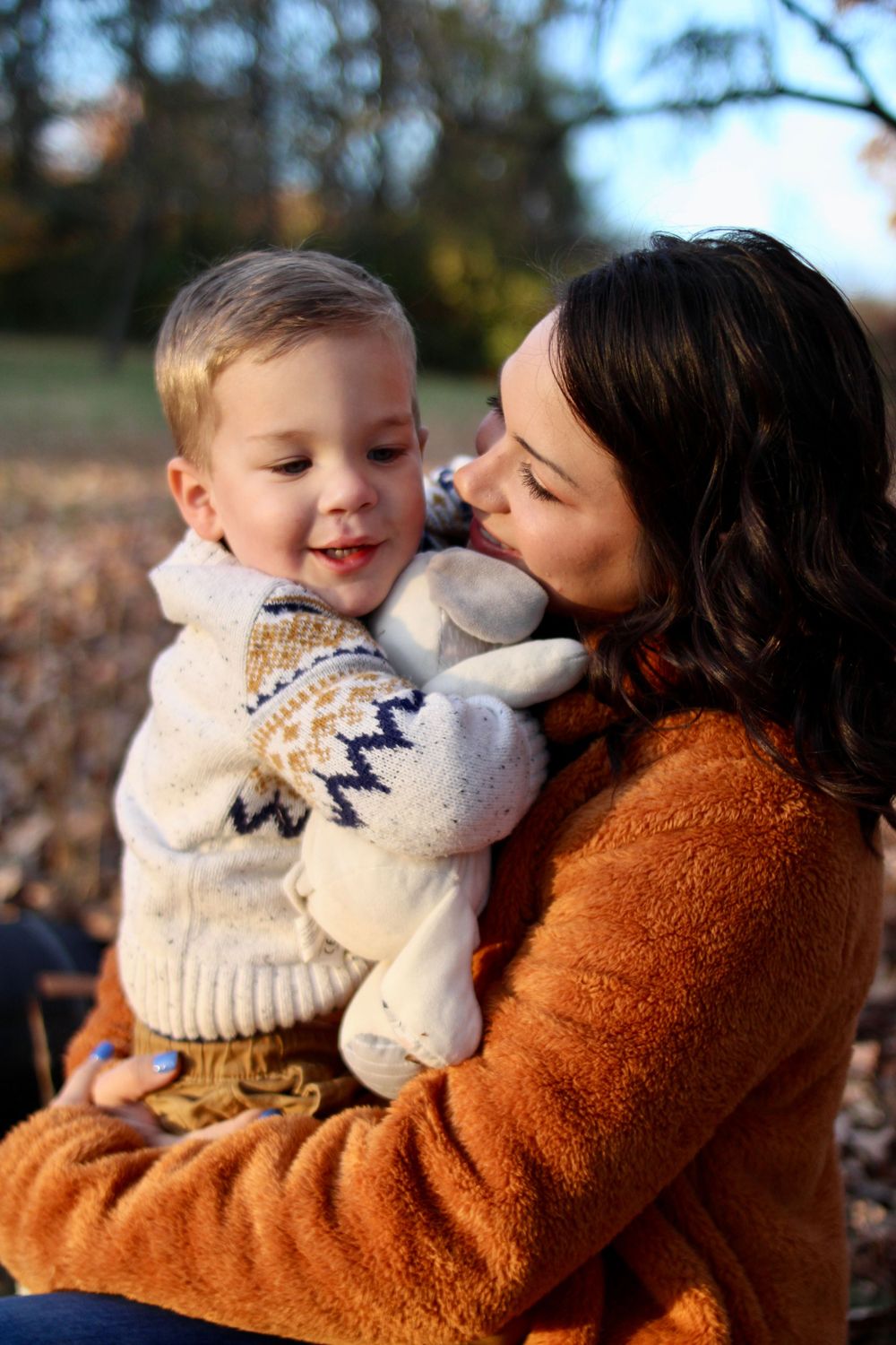 Mother and baby share tender moment during autumn outdoor photoshoot.