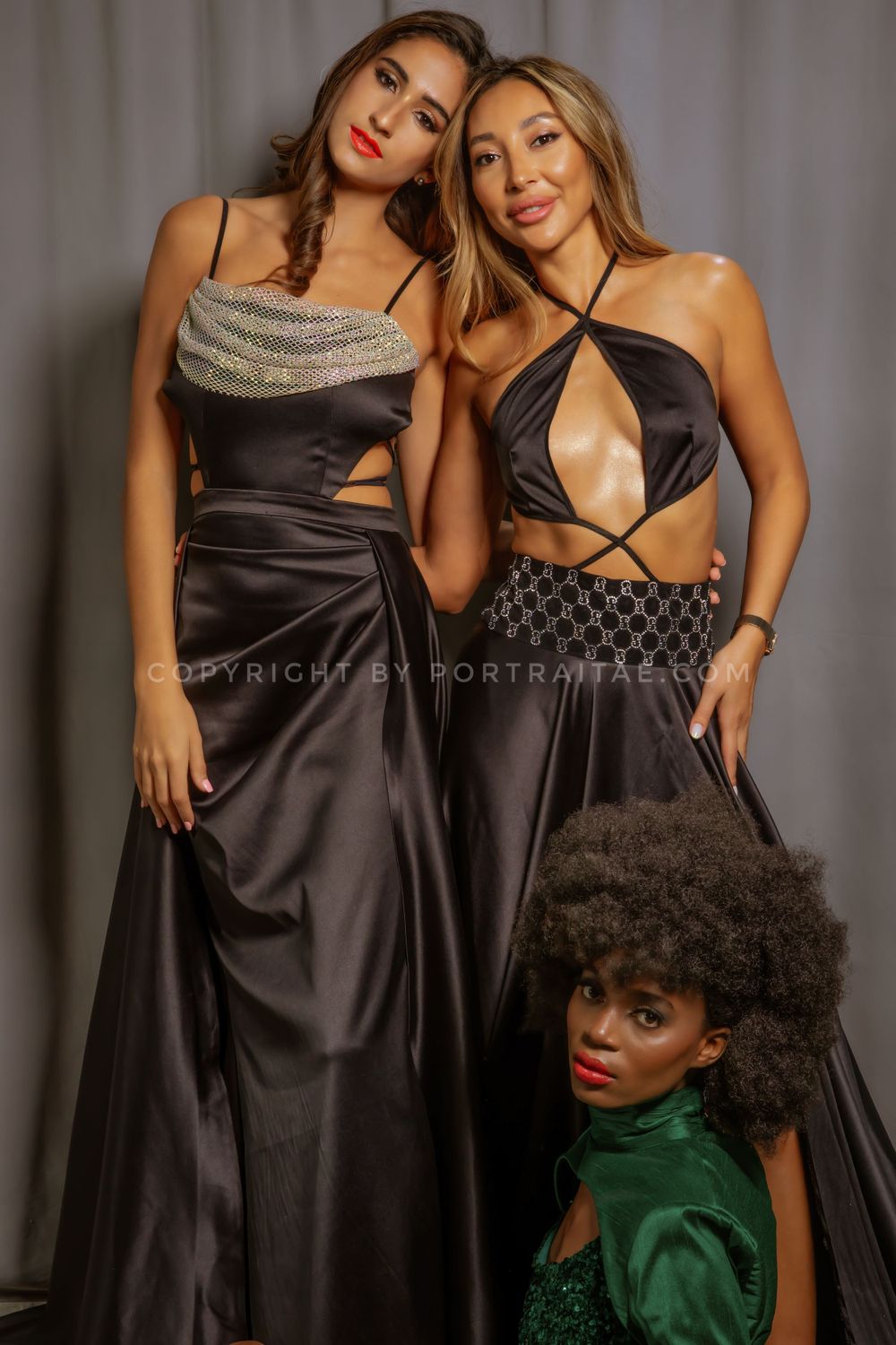 3 girls posing beside gray background with sexy black dress