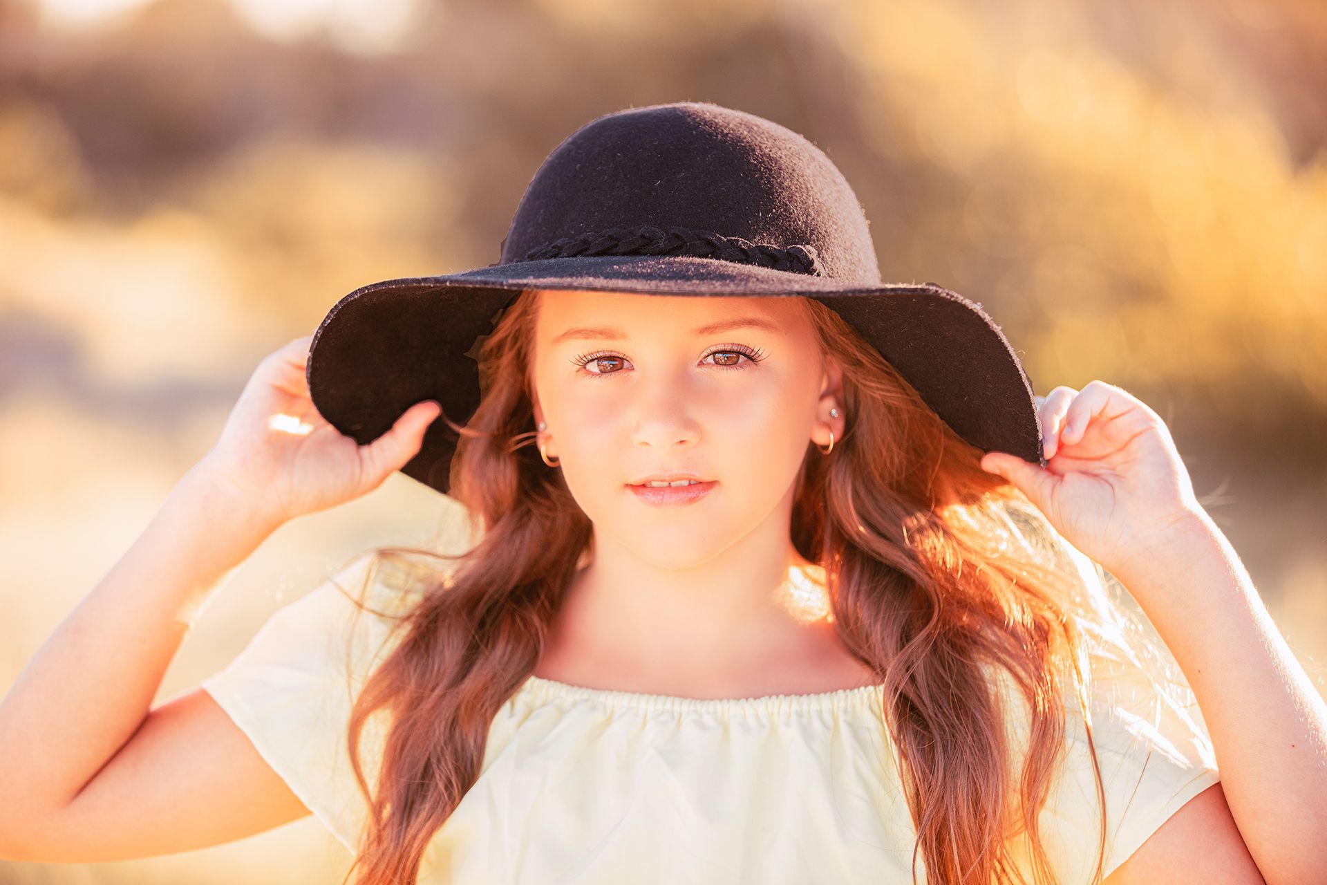 Silhouette of person in wide-brimmed hat against golden sunset sky.