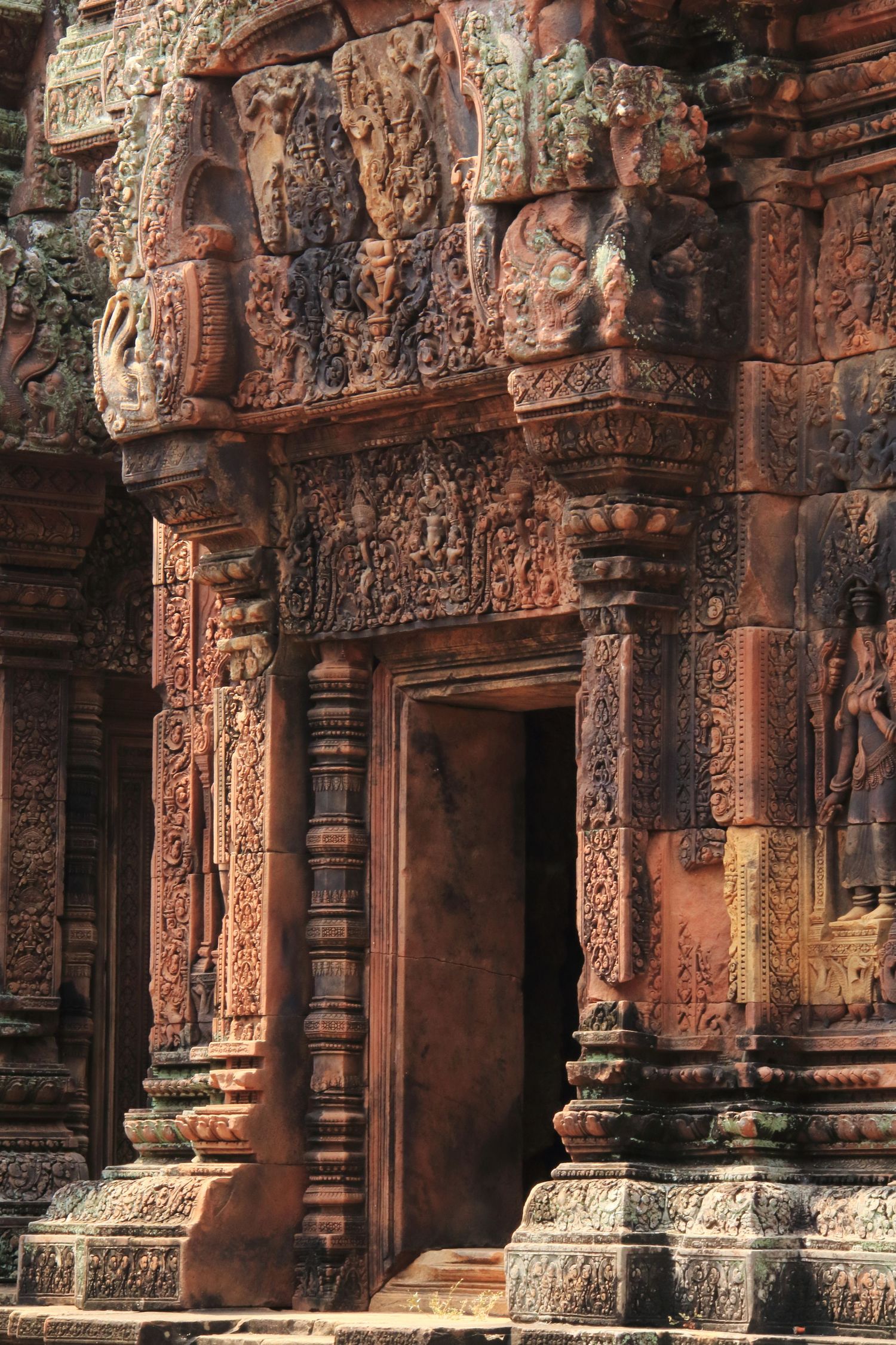 Intricately carved red sandstone temple doorway with detailed Khmer architecture.