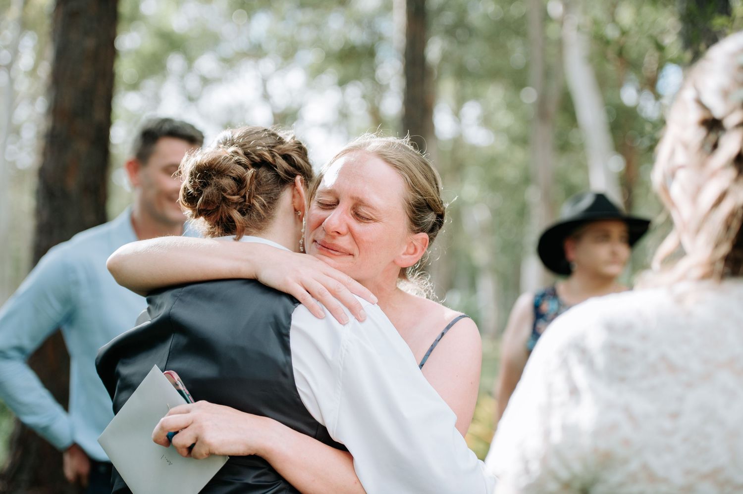 Emotional embrace shared between wedding attendees during outdoor celebration.