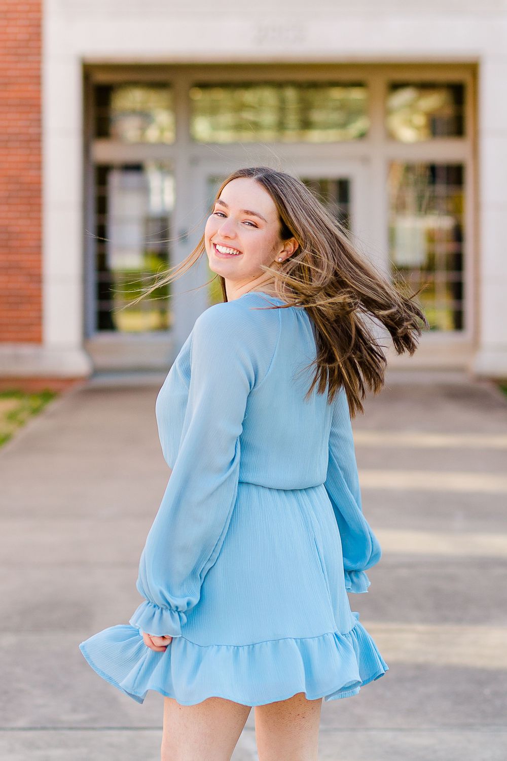 A carefree twirl in a light blue dress captures joyful movement outdoors.