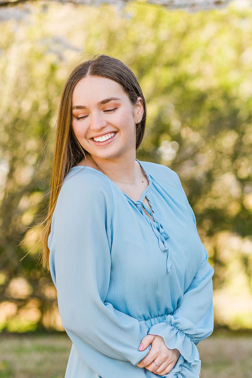 Portrait in light blue blouse with natural sunlit background outdoors.