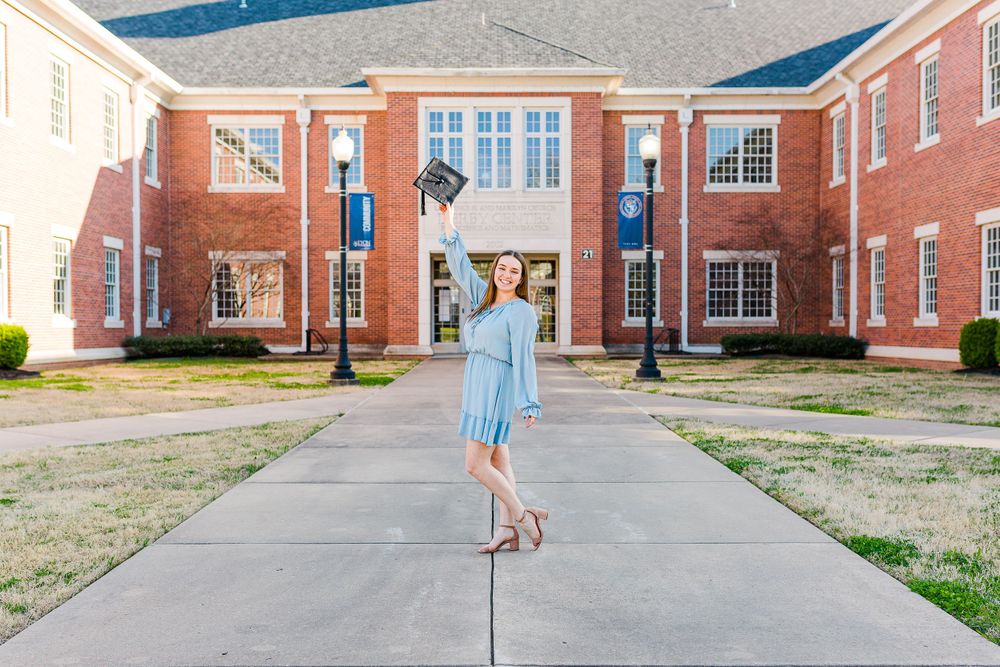A light blue dress stands out against red brick architecture on a campus walkway.