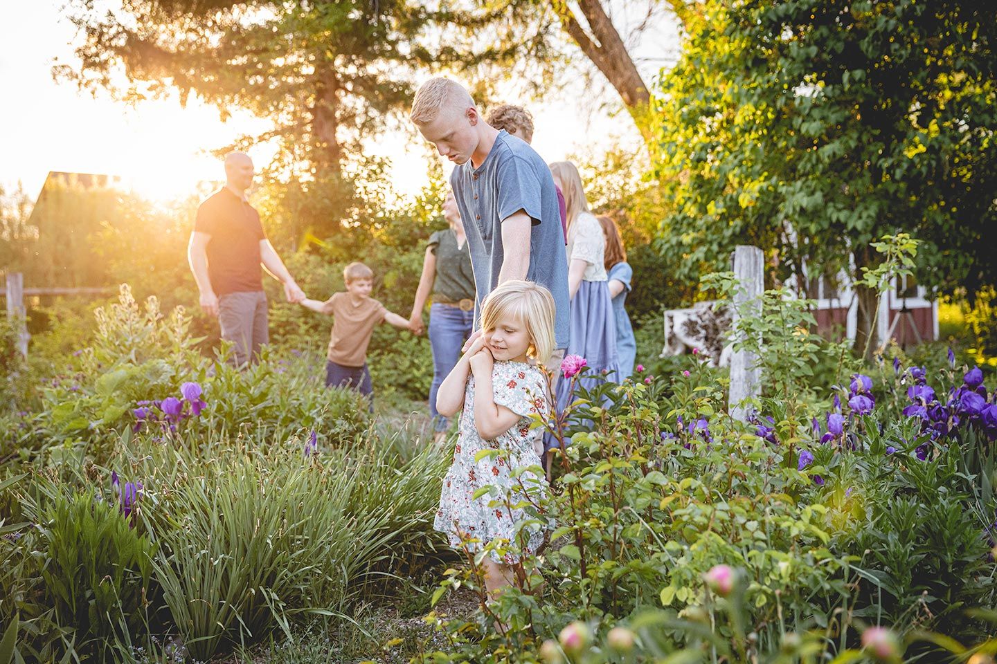 little sister holding brother's hand and guiding family through flowers