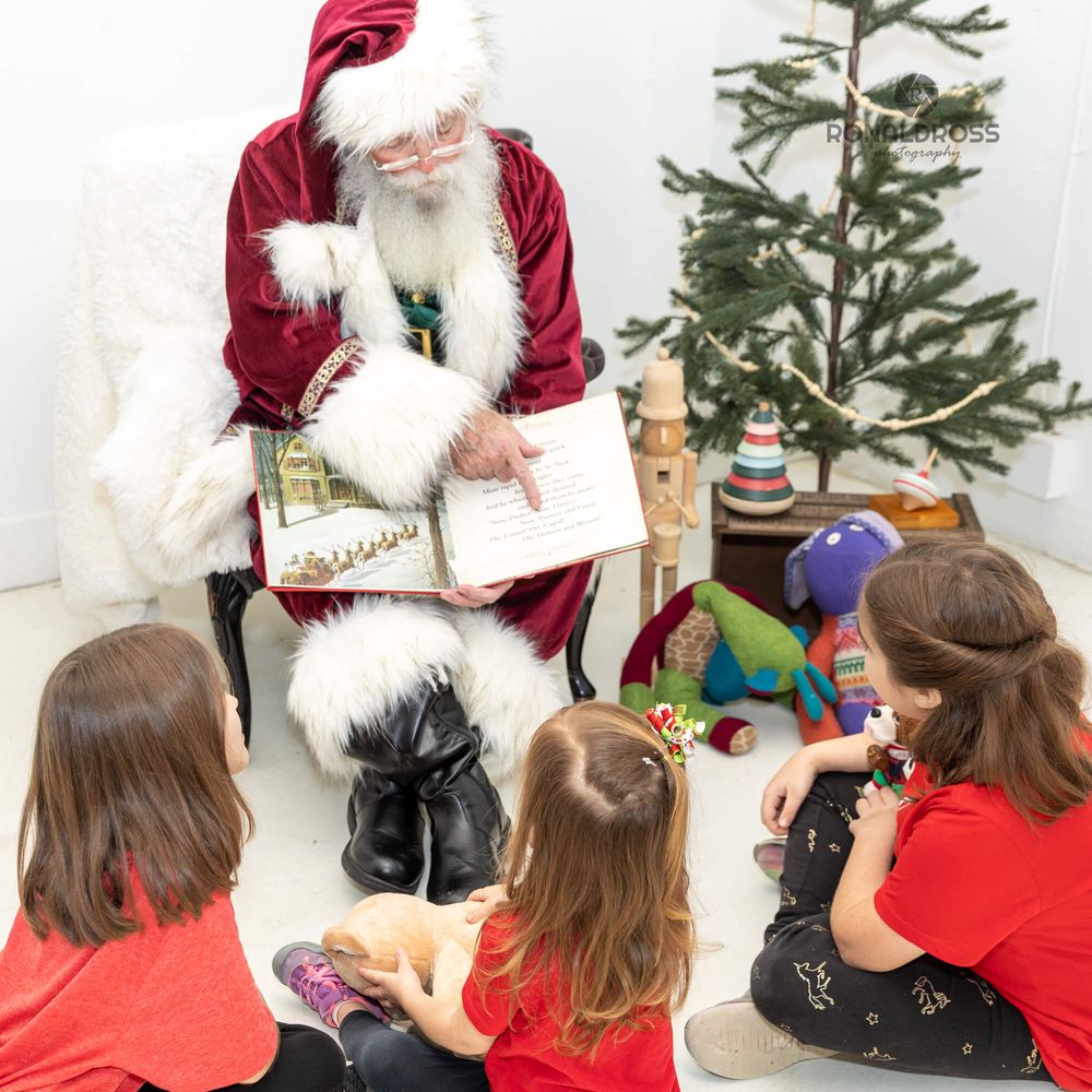 Children gathered around Santa Claus reading stories during a Christmas photo session.
