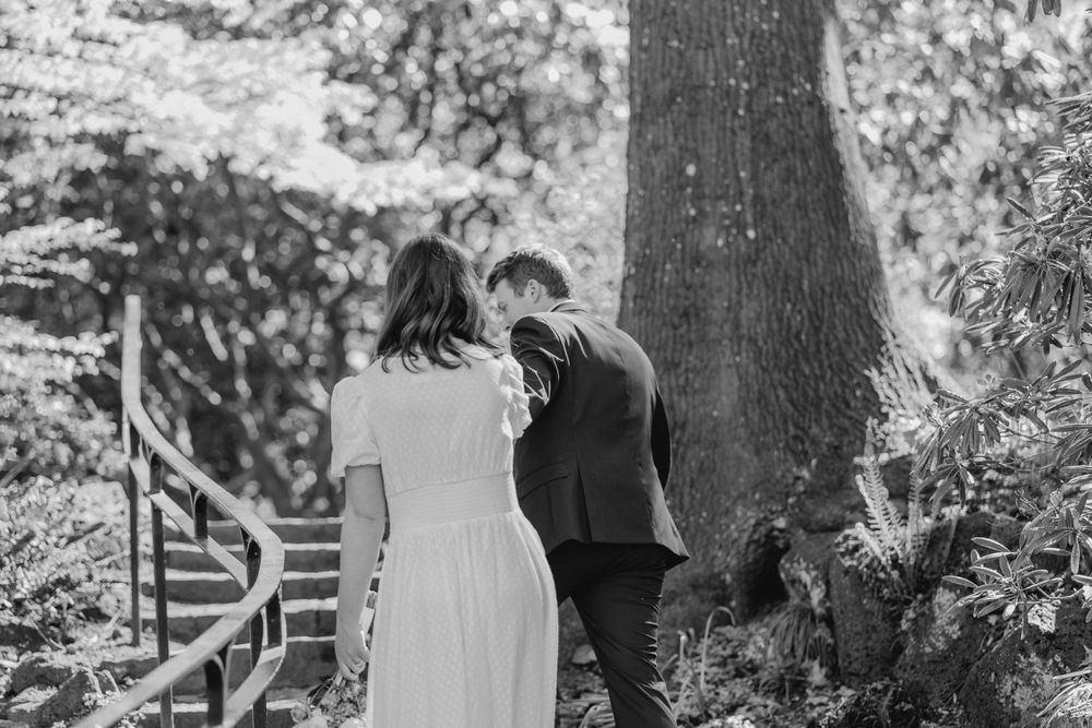 Black and white of Groom leading Bride up a winding staircase