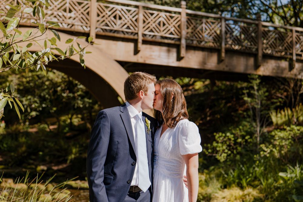 Bride and groom kissing with stone bridge in background