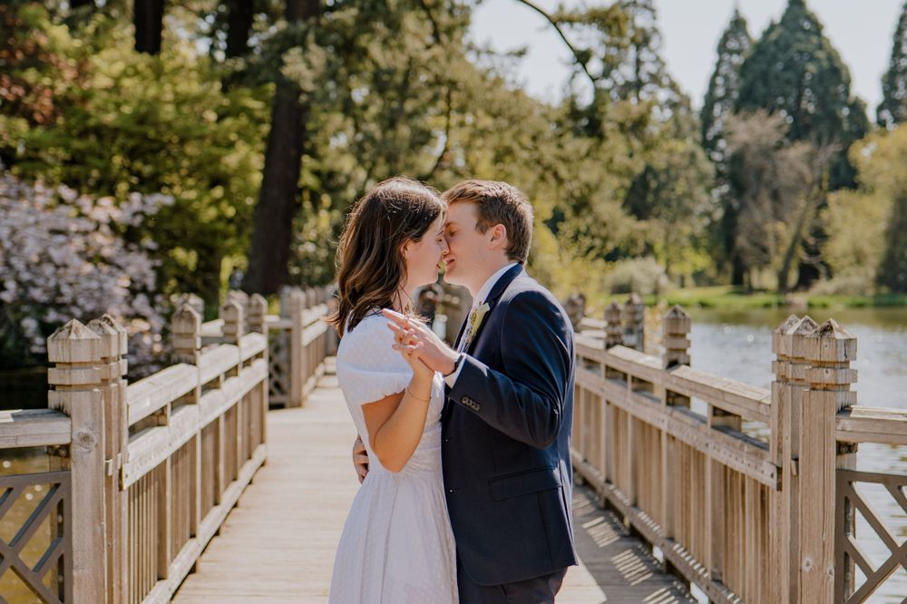 Bride and groom holding hands and kissing on stone bridge