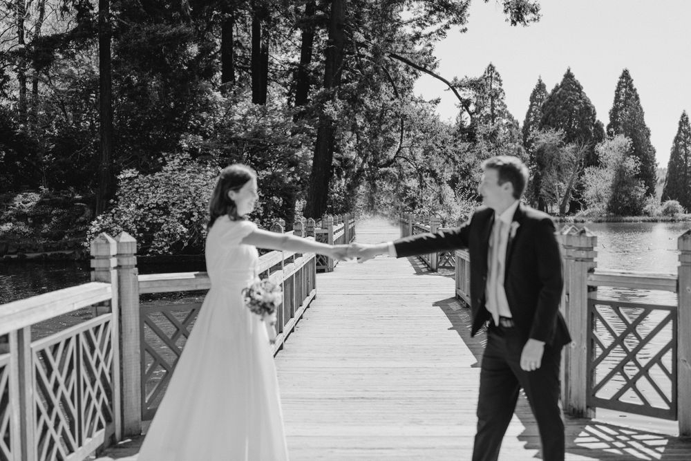 Black and white of Bride and groom dancing on stone bridge
