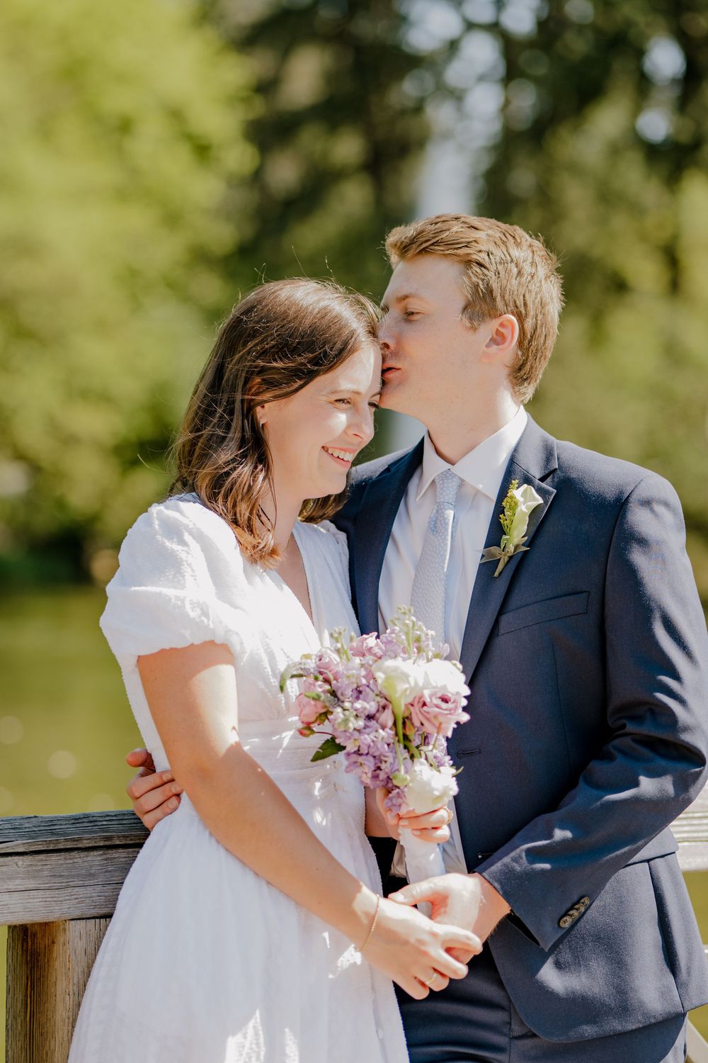 Groom kissing bride on the forehead whole hugging