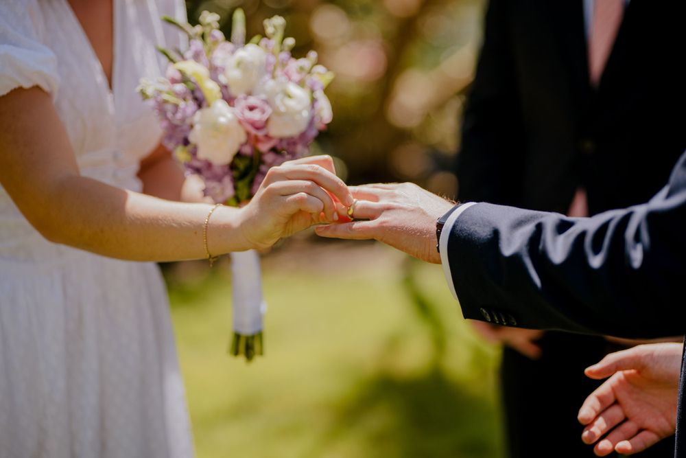 Bride placing ring on Groom's finger