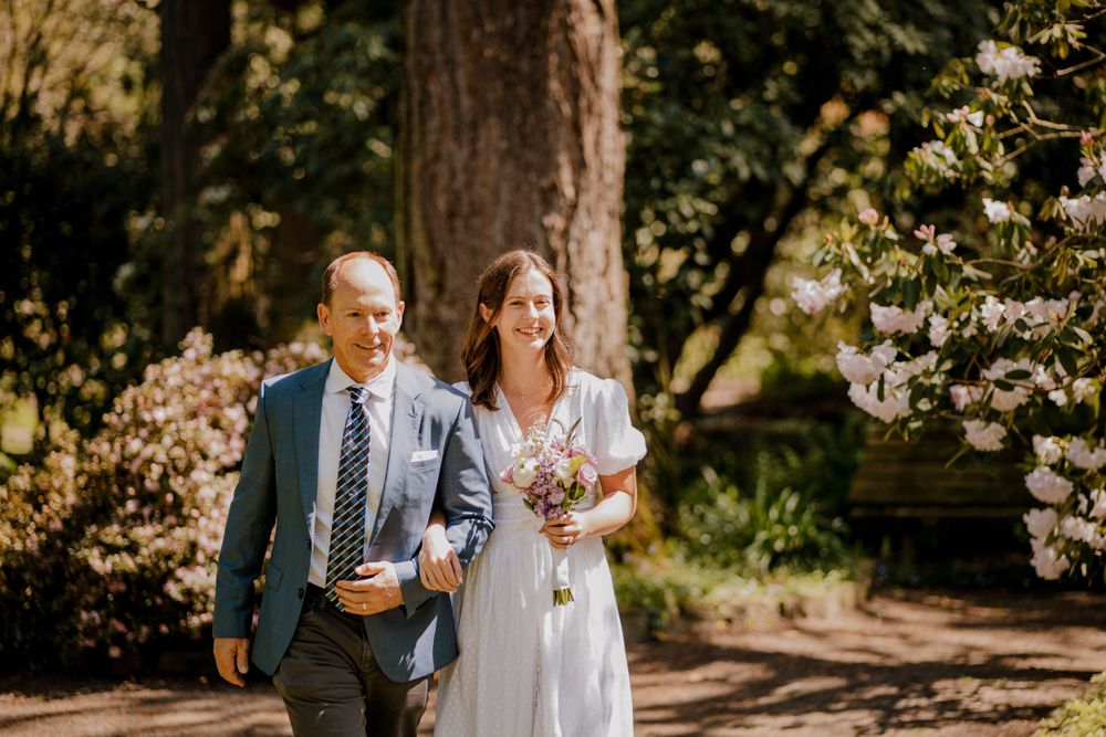 Bride and Father walking arm in arm in forest