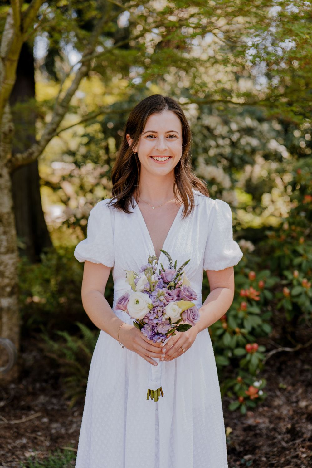 Bride standing in dress with purple and white bouquet