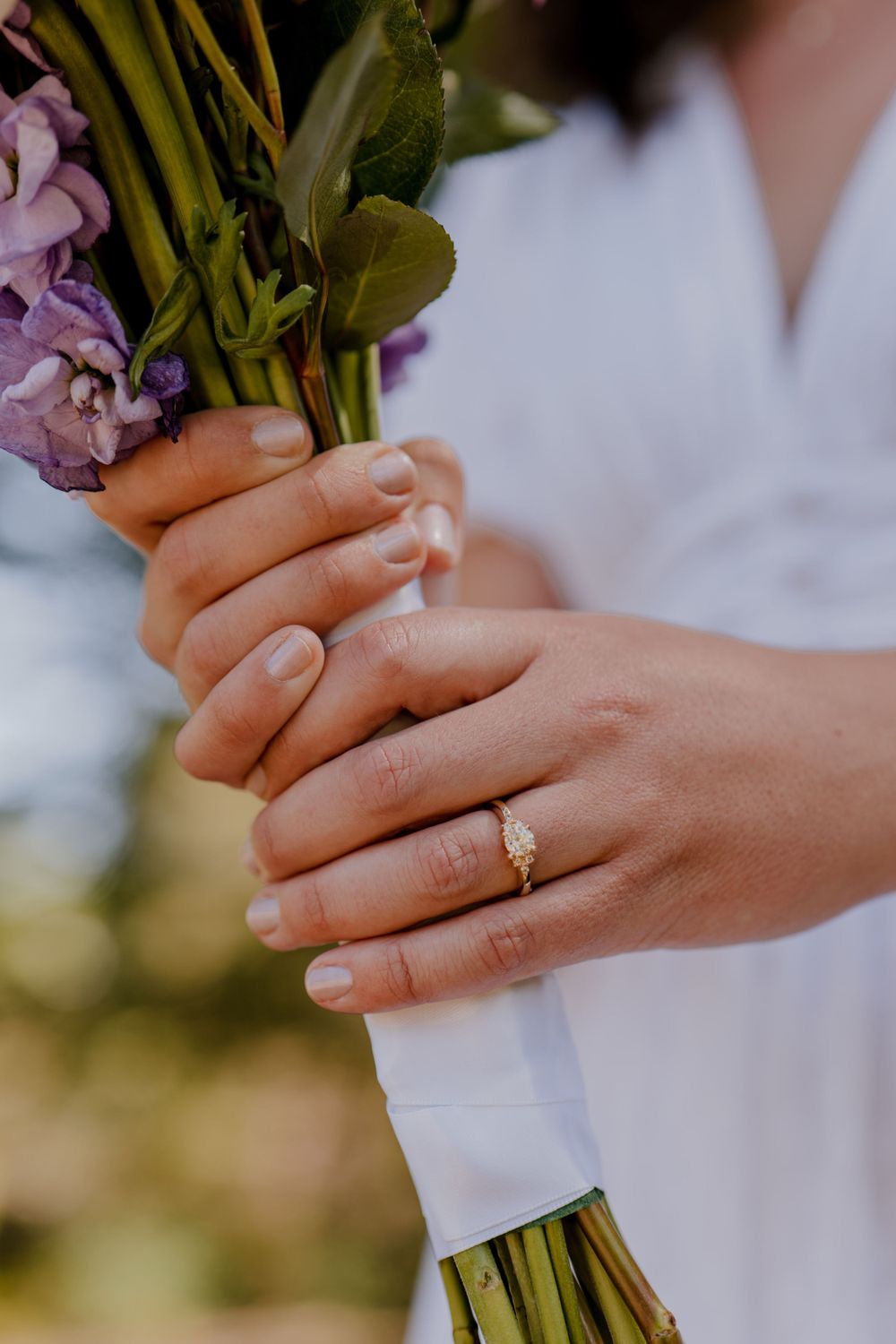 Close shot of bride's hand holding bouquet with wedding ring