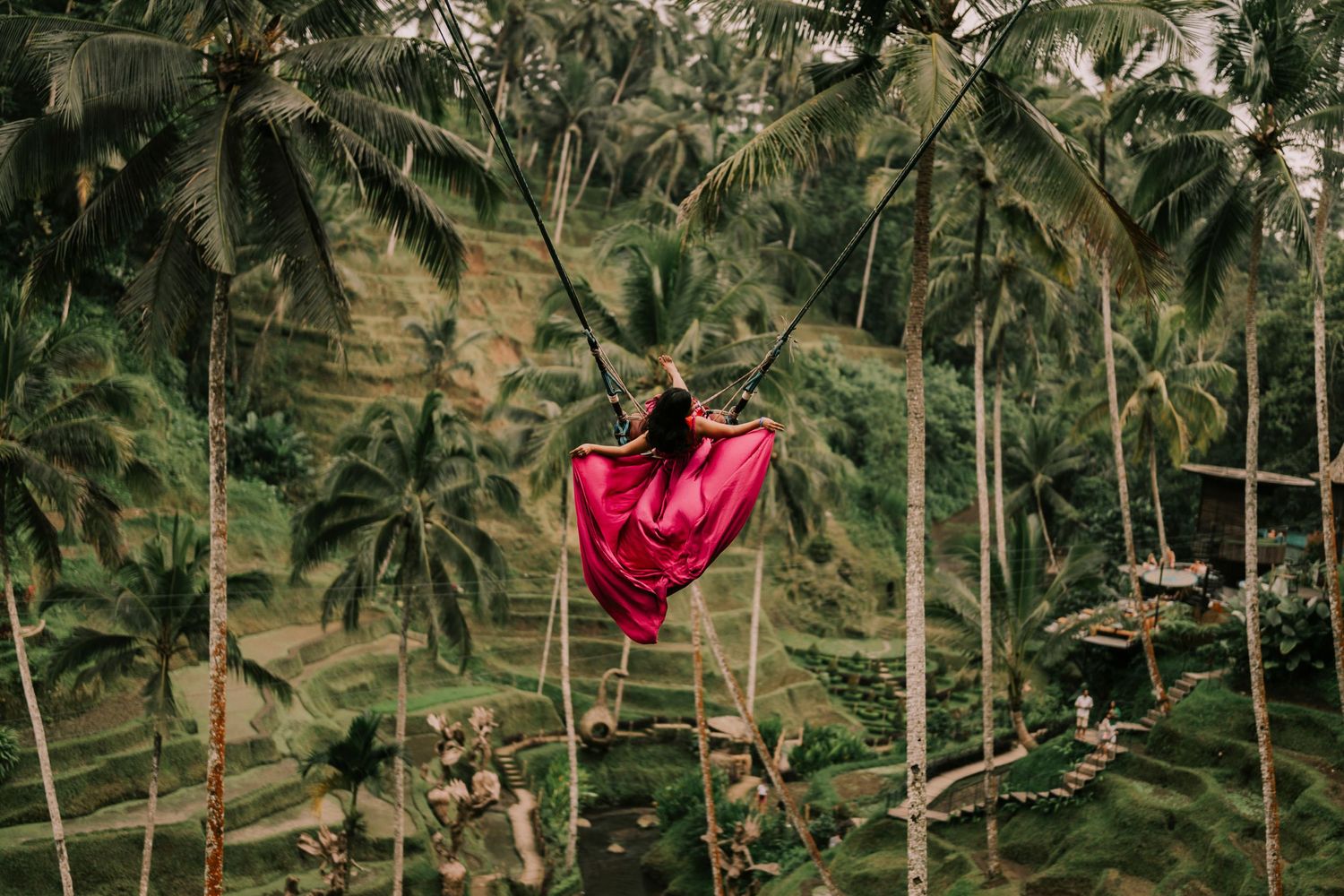 Red fabric flowing in the wind among tropical palm trees.