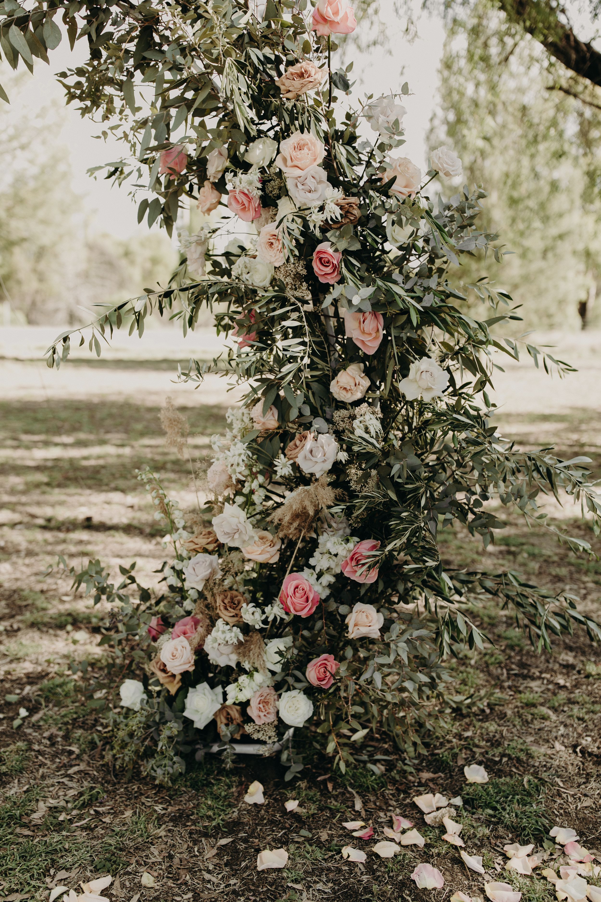 Romantic floral arch with pink and white roses cascading down in an outdoor garden setting.