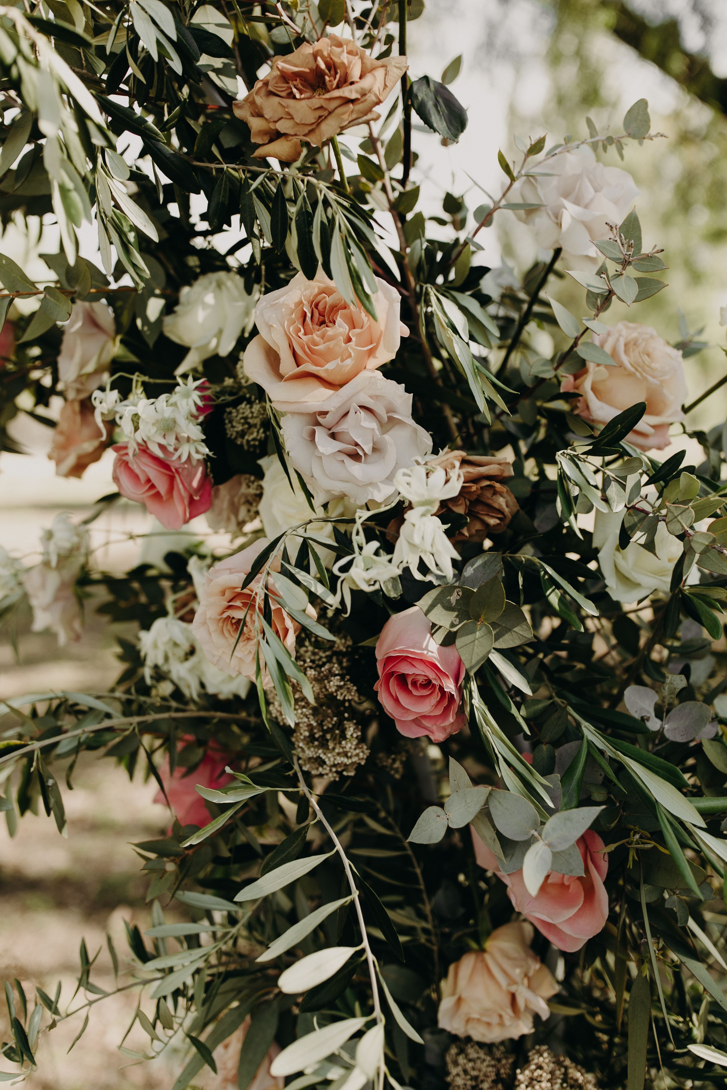 Lush floral arrangement featuring pink roses and white blooms intertwined with green foliage.